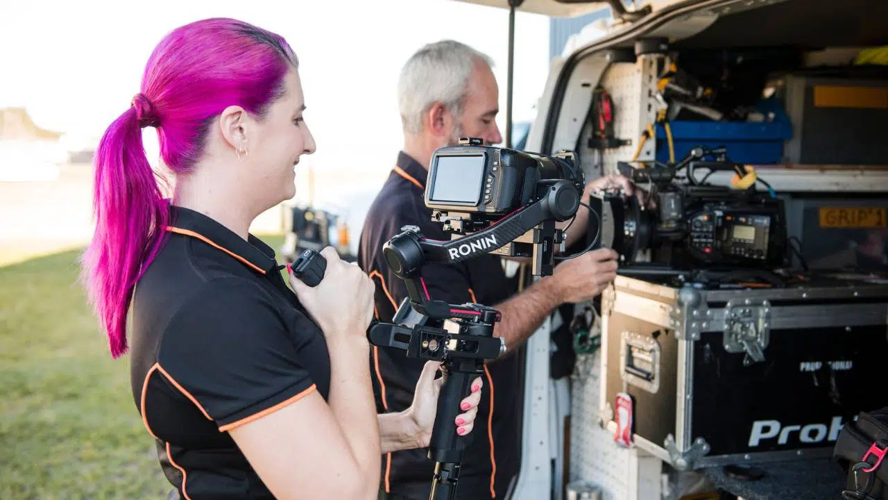 We film-with-two-cameras Sound images camera team of two unloading filming equipment from back of van