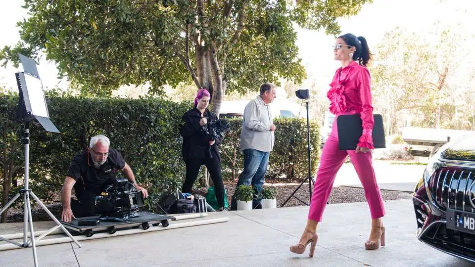 Let's wrap this up Model in pink outfit walking in front of cameras