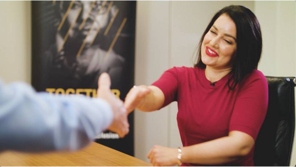 Corporate video production 1 Woman executive reaching across desk t shake hands